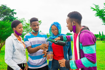 happy african friends turning drink into their cup - friendship concept