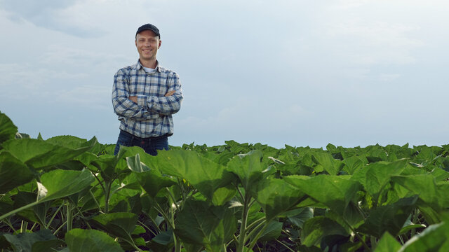 Portrait of a successful young farmer standing in the middle of a field and smiling while looking at the camera