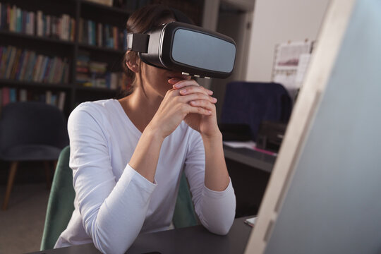 Mixed race woman using her VR googles on desk during coronavirus covid19 pandemic