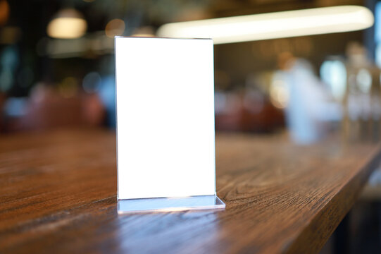 Mock up Menu frame standing on wood table in Bar restaurant cafe. space for text.
