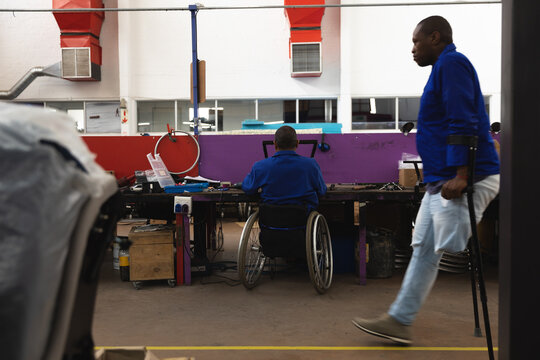 Disabled workers creating wheelchairs equipment in wharehouse - Powered by Adobe