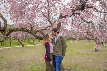 Happy couple with a tree of beautiful flowers on the background in spring season