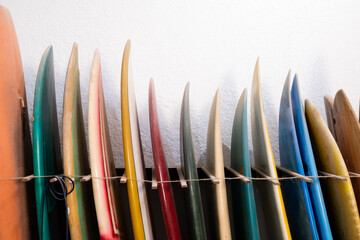View of a set of colorful surfboards put in a rack by the wall in a surfboard makers studio