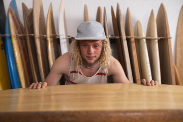 Caucasian male surfboard maker in his studio inspecting one of the surfboards
