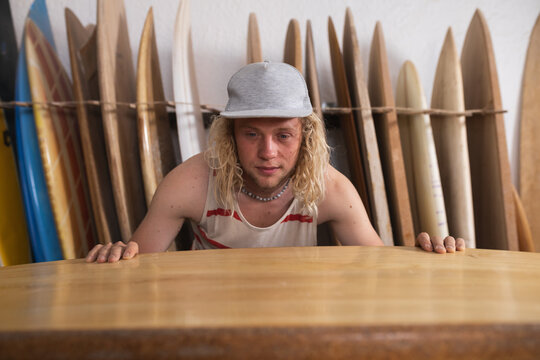 Caucasian male surfboard maker in his studio inspecting one of the surfboards