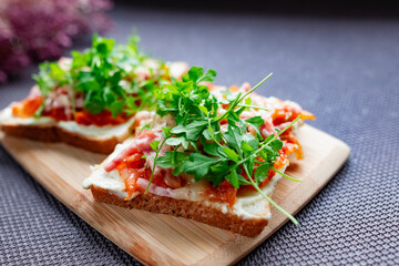 Baked hot sandwiches on white bread with fried vegetables in tomato sauce, Servelat straws, melted cheese and green watercress on a wooden Board