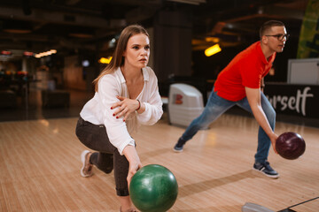 Fototapeta na wymiar A beautiful loving caucasian couple throwing balls on the bowling alley. Boyfriend and girlfriend at the bowling club