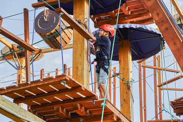 Boy standing on a wooden platform in a rope park