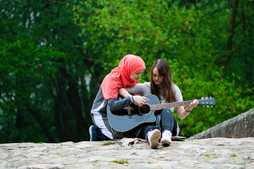 Two young muslim girls having guitar class