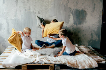 Family playing time. Mom and sons joke and fight pillows. Family fan. 
Lifestyle Portrait