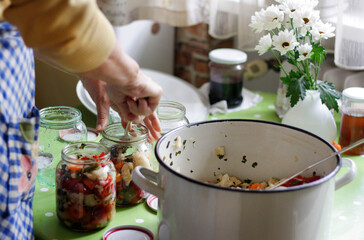 A woman fill up jars with pickle for the winter