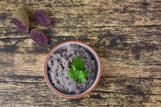 Vitelotte Mashed Purple Potato In A Bowl On Wooden Background Garnish With Parsley. Top View