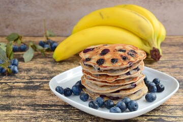 Homemade banana blueberry pancakes on wooden background