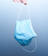 Woman hand holding a medical mask throwing it away