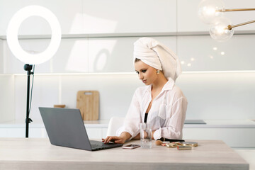 Cute young attractive woman with a towel on her head doing morning skin care procedures. Girl is...