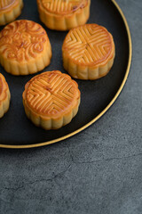 Mooncakes for the Mid-Autumn Festival are placed on a black plate with gold ornaments