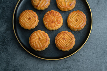 Moon cakes for the Mid-Autumn Festival are placed on a black plate with gold trim