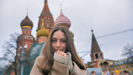 Happy smiling young woman portrait in Red Square, Moscow. A woman in the city warms her hands.