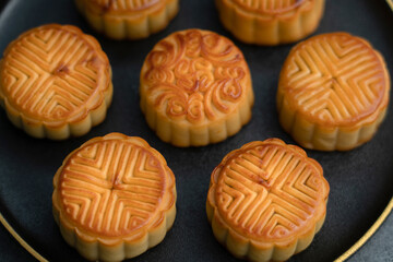 Mooncakes for the Mid-Autumn Festival are placed on a black plate with gold ornaments