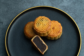 Moon cakes for the Mid-Autumn Festival are placed on a black plate with gold trim