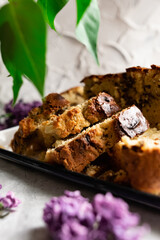 A large pie, cut into portions, stuffed with fruit and berries, among the branches of purple lilac blooming in spring. Homemade cakes on a tea tray.