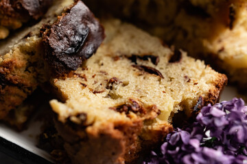 A large pie, cut into portions, stuffed with fruit and berries, among the branches of purple lilac blooming in spring. Homemade cakes on a tea tray.