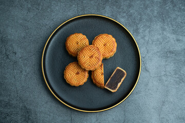Moon cakes for the Mid-Autumn Festival are placed on a black plate with gold trim