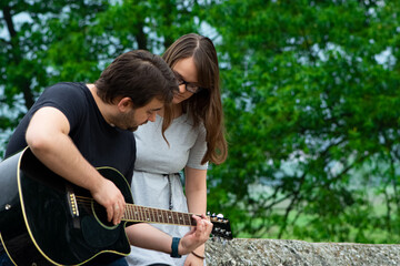 Brother teaching sister to play guitar in nature