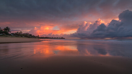 A colourful sunrise with large clouds drifting towards the land