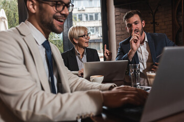 Senior businesswoman holding a meeting with her younger colleagues at cafe.