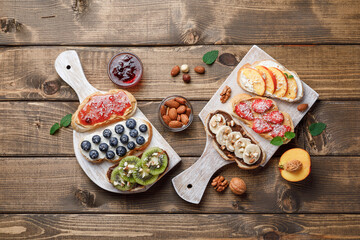 Sweet sandwiches with fruits and berries on wooden background.