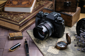 A camera, a wooden box, a book, a compass, a fountain pen on a wooden table.