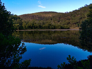 Fototapeta na wymiar Creek with beautiful reflections of blue sky, mountains and trees, Crosslands Reserve, Berowra Valley National Park
