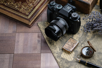 A camera, a wooden box, a book, a compass, a fountain pen on a wooden table.