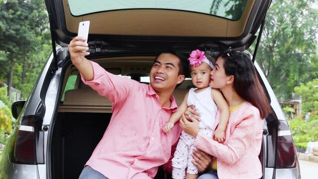 Cheerful family taking selfie picture in car trunk