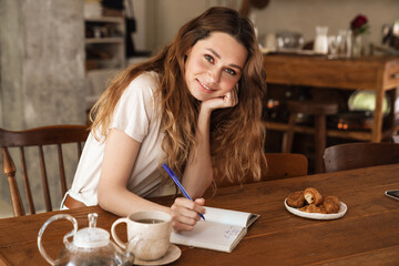Lovely cheerful young girl sitting at the kitchen table