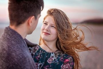 The girl looks tenderly at her young man. Close-up of a girl with her hair flying in the wind . Love, trust, always be together concept
