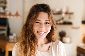 Cheerful lovely girl grimacing while standing in the kitchen