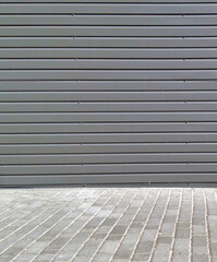 Corrugated sheet metal dark gray facade and light gray pavement