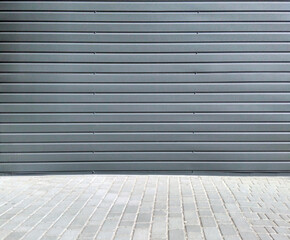 Corrugated sheet metal dark gray facade and light gray pavement
