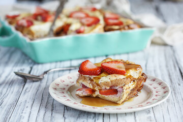 Strawberry cheesecake French toast casserole with maple syrup. Made with cream cheese and strawberries. Selective focus with blurred background.
