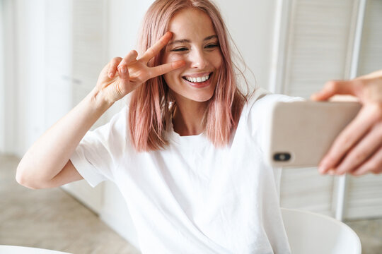 Cheerful young girl taking a selfie indoors