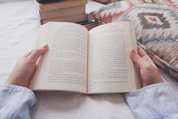 Close up image of a person reading books at home.