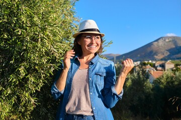 Portrait of mature beautiful smiling woman in hat, jeans clothes, copy space