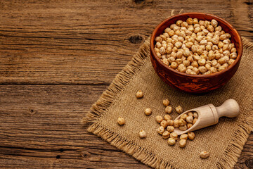 Dry chickpea in ceramic bowl on old wooden boards background. Traditional ingredient for cooking hummus