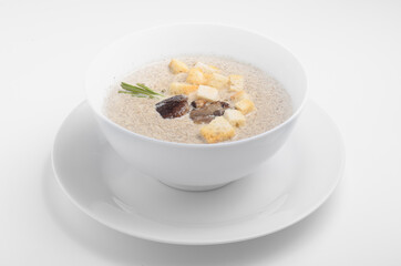 Cream soup with mushrooms and garlic croutons. Served in a white plate on a white background. For use in online food ordering catalogs and menus or culinary publications