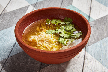 Classic chicken broth in brown pottery bowl