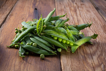 open pods of green peas on a wooden table close-up, harvest from the garden