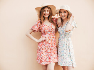 Two young beautiful smiling hipster girls in trendy summer sundress.Sexy carefree women posing on...