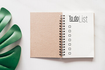 Notebook with to do list words on white marble texture background.